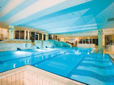 Großes Hallenbad mit mehreren Schwimmbecken und hellem Ambiente in einem Hotel.
