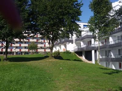 Modernes Hotelgebäude mit Balkonen und grünem Rasen im Vordergrund