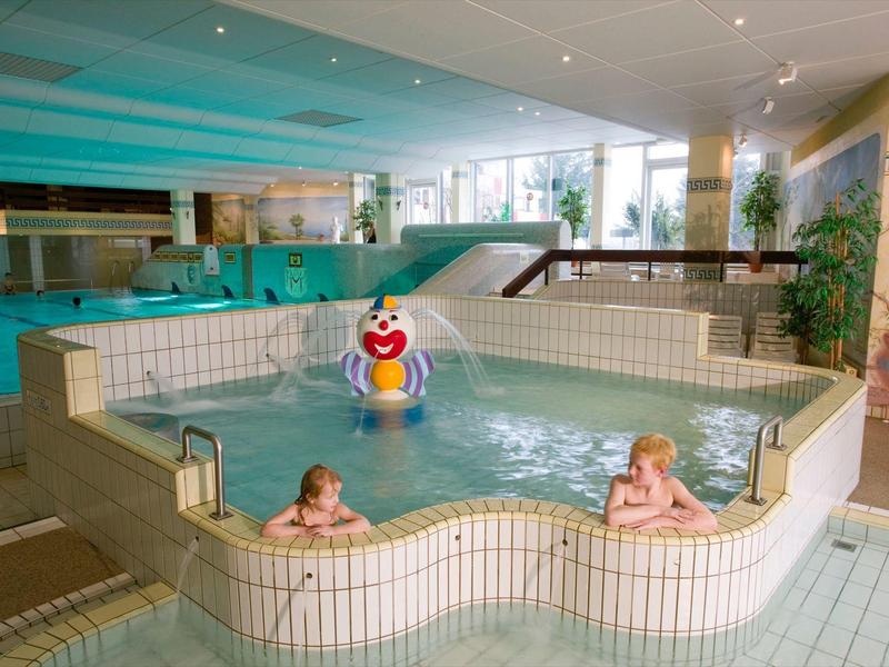 Innenpool mit separatem Kinderbecken und buntem Spielzeug in einem Hotel.