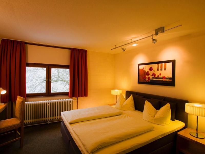 Gemütliches Hotelzimmer mit Doppelbett, Schreibtisch und warmem Licht.