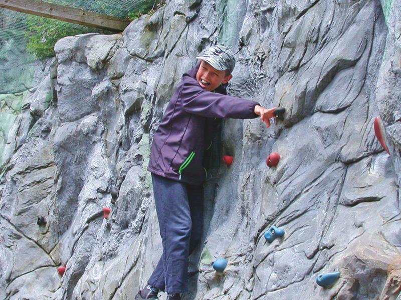 Person klettert an einer Kletterwand in einer Indoor-Anlage