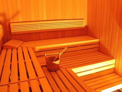 Holzsauna mit mehrstufigen Bänken, Eimer und Schöpfkelle, warmes Licht, klare Linien.