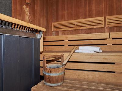 Gemütliche Sauna mit Holzbänken, Holzeimer und hölzernem Wasserkübel.