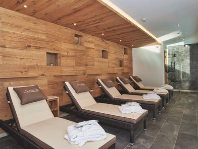 Moderne Wellness-Liegeflächen mit Holzwand und schwarzen Kissen in hellem, ruhigem Raum.