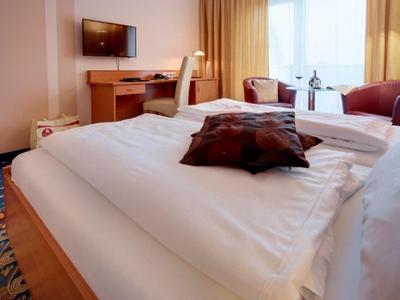 Nowocześnie urządzone pokój hotelowy z łóżkiem podwójnym, biurkiem i telewizorem.