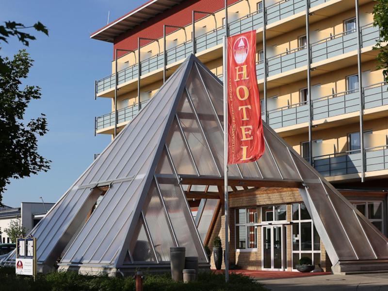 Nowoczesny hotel z szklaną strukturą piramidy przy wejściu.