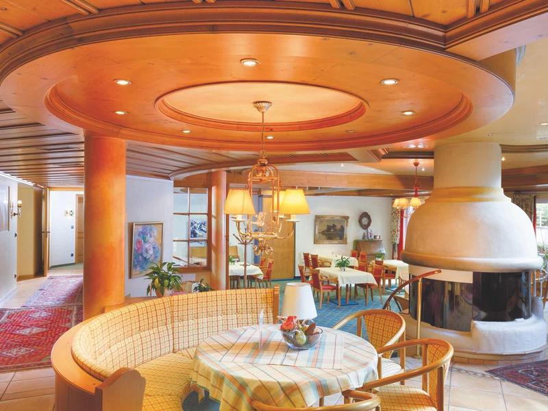 Accogliente area lounge dell'hotel con tavoli rotondi, poltrone e camino aperto.