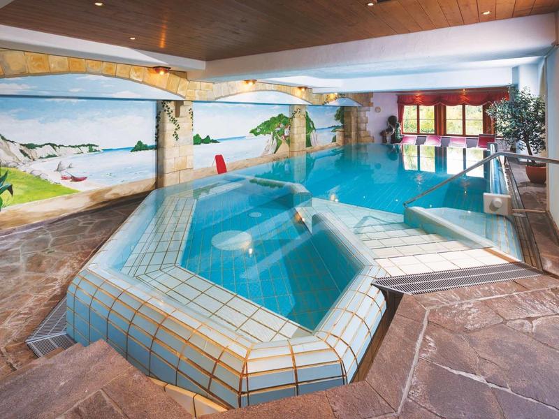 Piscina coperta con piastrelle a mosaico e murales, atmosfera accogliente nell'area benessere.