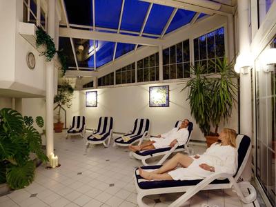 Relaxed guests lie on loungers in a cozy, heated conservatory.