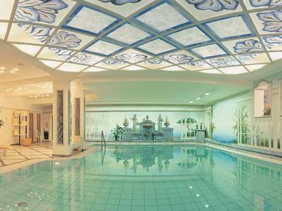 Großes Hallenbad mit Tageslicht durch Kuppelfenster und Liegestühlen im lichtdurchfluteten Raum