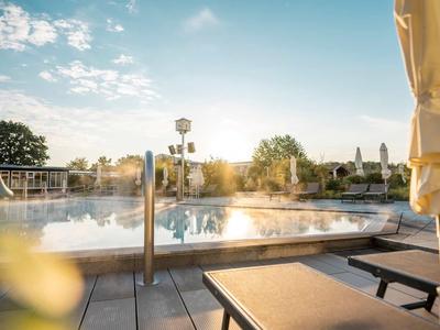 Außenpool mit Sonnenliegen und Sonnenschirm bei Sonnenaufgang