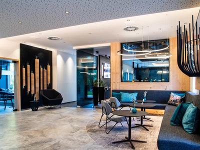 Moderner Wartungsbereich mit blauen Sofas, grauen Stühlen, Tischen und künstlerischer Wanddekoration.