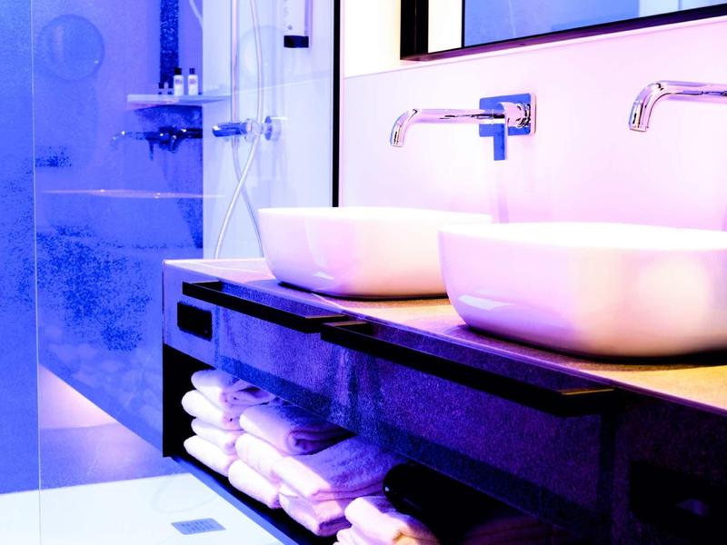 Modernes Badezimmer mit zwei weißen Waschbecken, wandmontierten Wasserhähnen und gefliester Dusche.