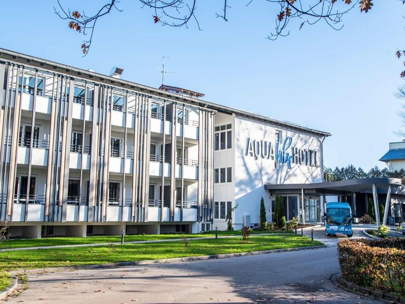 Mehrstöckiges Gebäude mit weißen Fassaden und blauem Schriftzug "AQUA SAUNA".