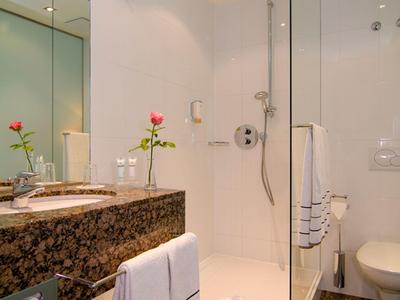 Salle de bain moderne avec douche en verre, lavabo en marbre et serviettes blanches.
