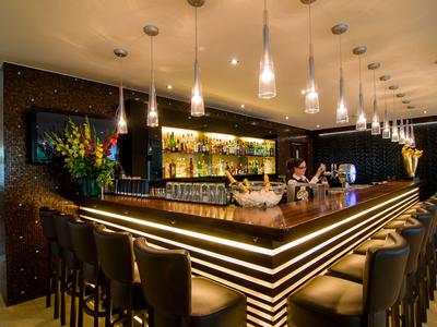 Bar moderne éclairée avec des tabourets en cuir hauts et décorations dans un hôtel.