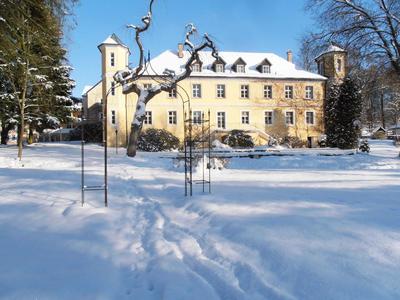 Schlossartiges Hotel mit Türmen in verschneiter Winterlandschaft und blauem Himmel.