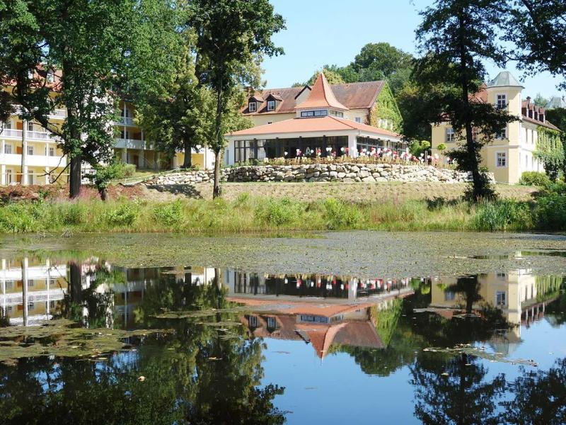 Bâtiment avec terrasse et arbres au bord d'un lac calme avec réflexion claire