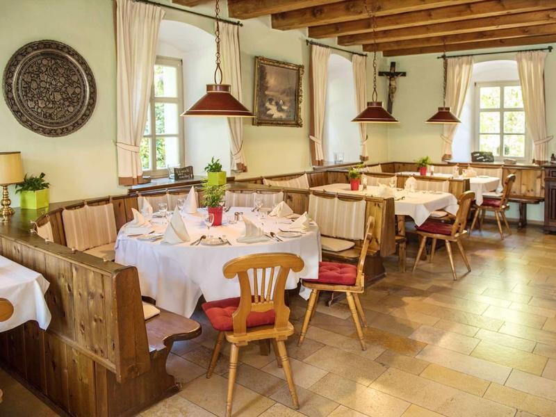Salle à manger confortable avec mobilier en bois, nappes blanches et vue sur les fenêtres