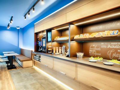 Moderner, heller Frühstücksraum mit Holzmöbeln, blauen Wänden und gedecktem Buffetbereich.