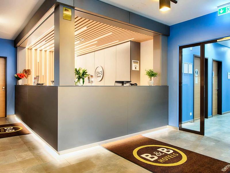 Moderner Empfangsbereich mit blauem Tresen, Holzelementen und mehreren Türen im Hintergrund.