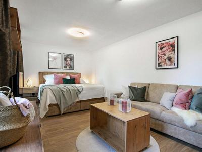 Modern eingerichtetes Hotelzimmer mit Bett, Sofa und Holz-Couchtisch auf Holzboden.