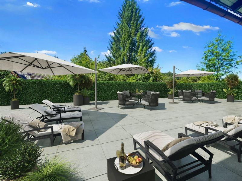 Große Terrasse mit grauen Steinplatten, Sonnenliegen, Sitzgruppen und weißen Sonnenschirmen bei blauem Himmel.