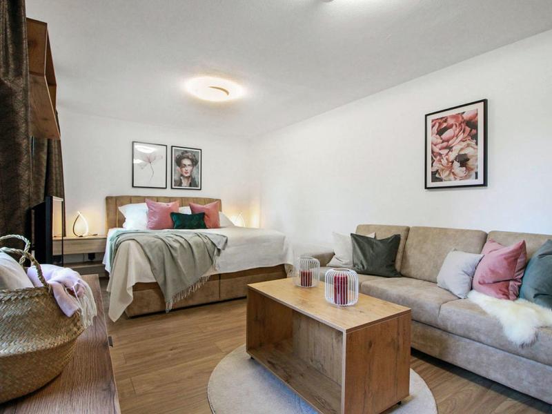 Gemütliches Schlafzimmer mit Doppelbett, Sofa, Holztisch und Wandbildern in sanften Farben.