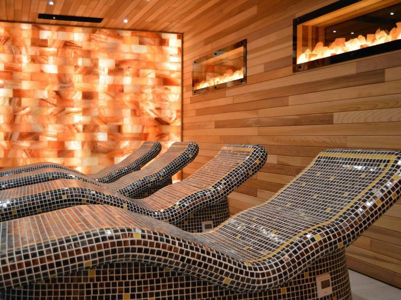 Ruheraum mit drei mosaic-geflecht Sonnenliegen vor einer warm beleuchteten Salzsteinwand.