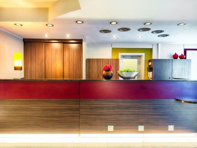 Réception d'hôtel moderne avec un comptoir rouge et couleur bois et des objets décoratifs.