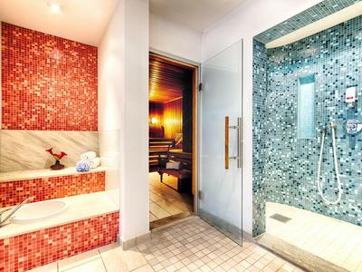 Moderne wellnessruimte met stoomdouche, sauna en zitbank met rode mozaïektegels.