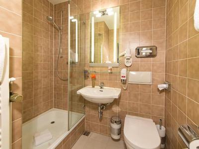 Compacte badkamer met douche, wastafel, toilet en bruine betegelde wanden.