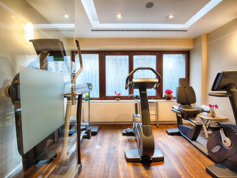 Moderne fitnessruimte met diverse trainingsapparatuur en houten vloer in een hotel.