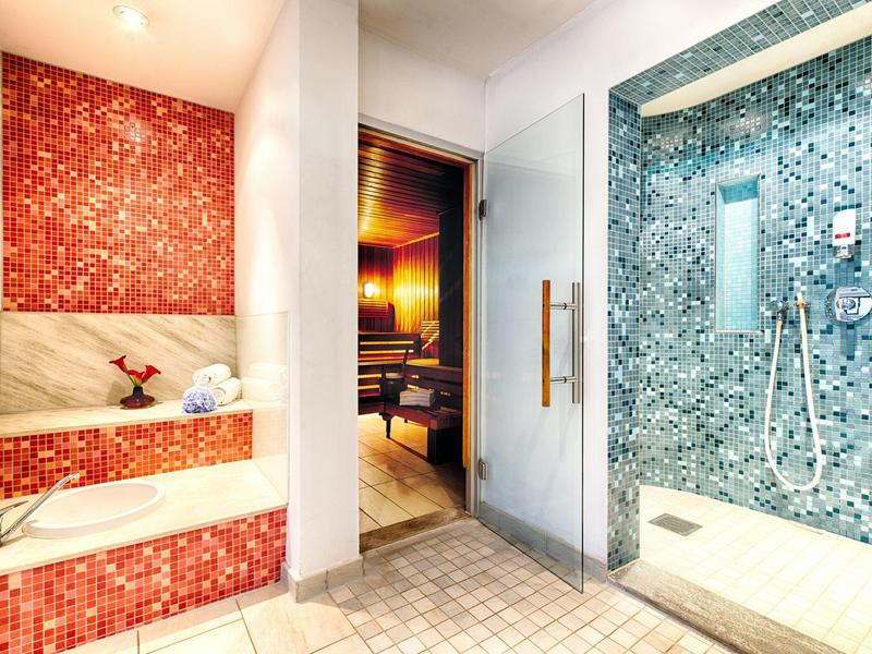 Moderne wellnessruimte met stoomdouche, sauna en zitbank met rode mozaïektegels.