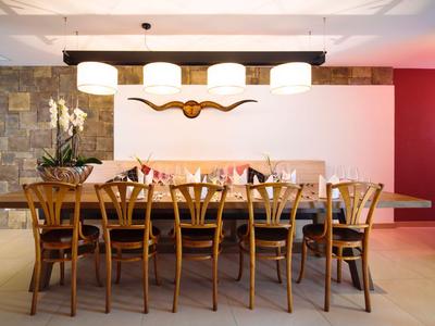 Zona pranzo moderna con tavolo in legno lungo, otto sedie e decorazione a parete con corno.