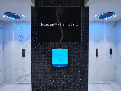 Dwie windy z niebieskim oświetleniem w nowoczesnym hotelu z kafelkową ścianą między nimi.