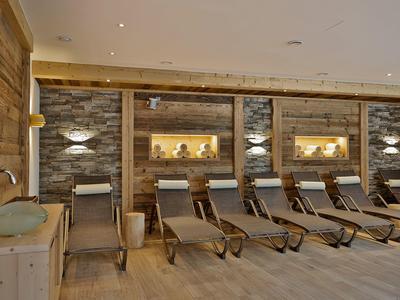 Ontspanningsruimte met ligstoelen voor een met steen beklede muur met verlichte nissen.