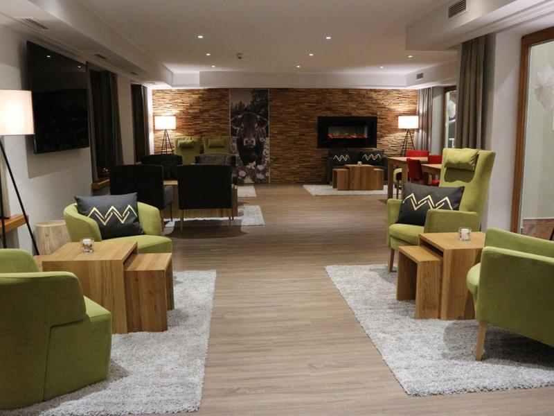 Modern ingerichte hotel lounge met groene fauteuils en warme verlichting.