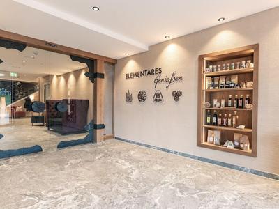 Entrée lumineuse du hall d'hôtel avec sièges, cloison en verre et étagère d'exposition avec boissons.