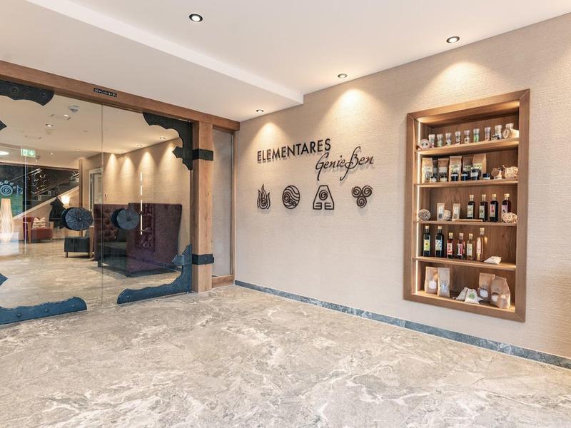 Moderne hotelentree met marmeren vloer, zitplaatsen en een plank met cake- en drinkbenodigdheden.