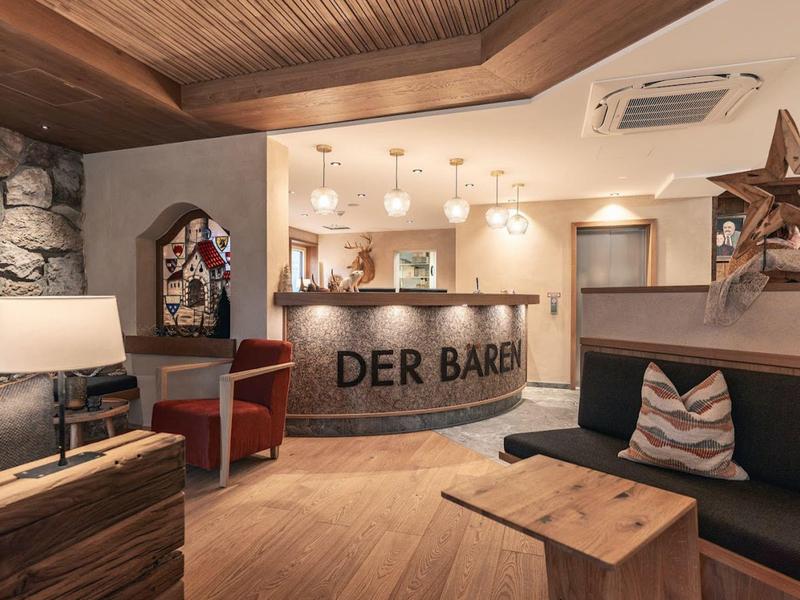 Gezellige hotelreceptie met houten balie, zitplaatsen en decoratieve verlichting.