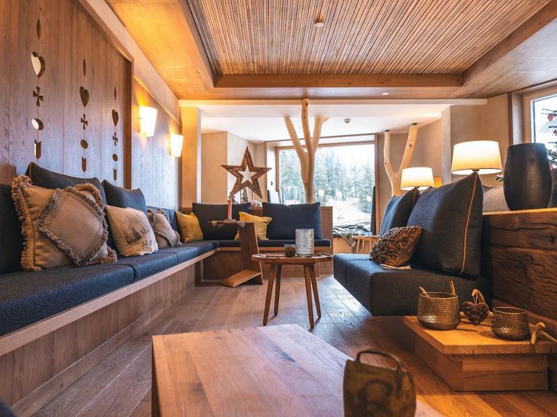 Gezellige lounge met houten balkenplafond, comfortabele fauteuils en grote ramen in een hotel.