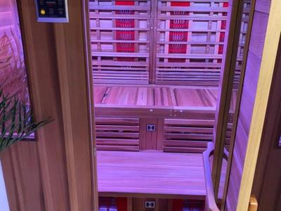 Interior view of an infrared sauna with wooden benches and purple lighting