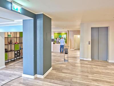 Hell beleuchteter Hotelflur mit Aufzügen und moderner Einrichtung.