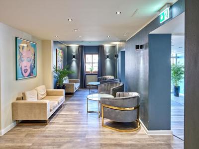 Moderner Hotel-Loungebereich mit bequemen Sesseln, Sofas und abstrakter Kunst an den Wänden.