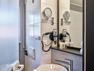 Moderner Hotelbadezimmer-Waschbeckenbereich mit rundem Waschbecken, Spiegel und Haartrockner.