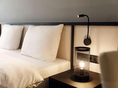 Modern eingerichtetes Hotelzimmer mit weißem Bett und Nachttischlampe