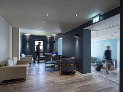 Moderner Lounge-Bereich mit Sesseln und Sofas, hellem Holzboden und schwarz gestrichenen Wänden