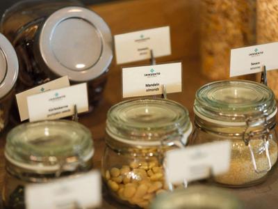 Various breakfast ingredients in glass jars with labels at a hotel buffet.