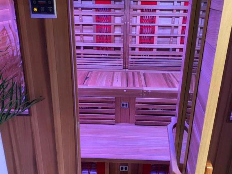 Interior view of an infrared sauna with wooden benches and purple lighting
